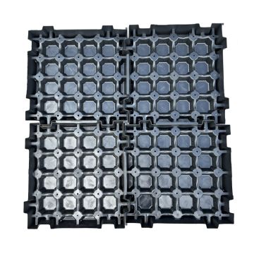 Four interlocking black plastic modular drainage tiles arranged in a 2x2 grid, showing their interlocking edge design and textured surface against a plain white background.